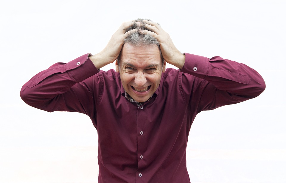 man stressed and covering his ears from the noise